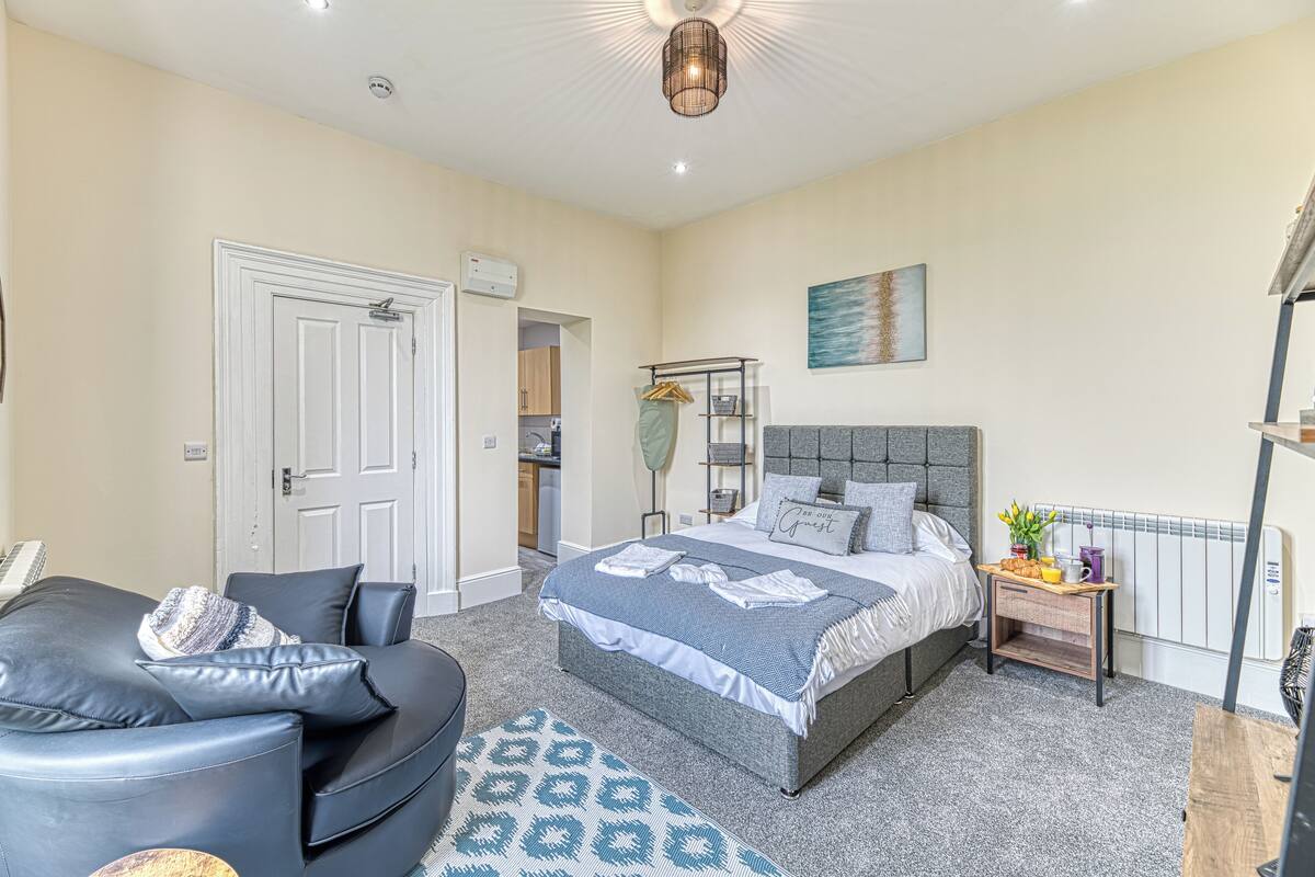 A bedroom with a bed, bedside table, and a seating area with a sofa and armchair.