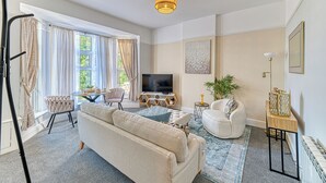 Una sala de estar con sofá, sillón, televisor y una mesita con objetos decorativos.