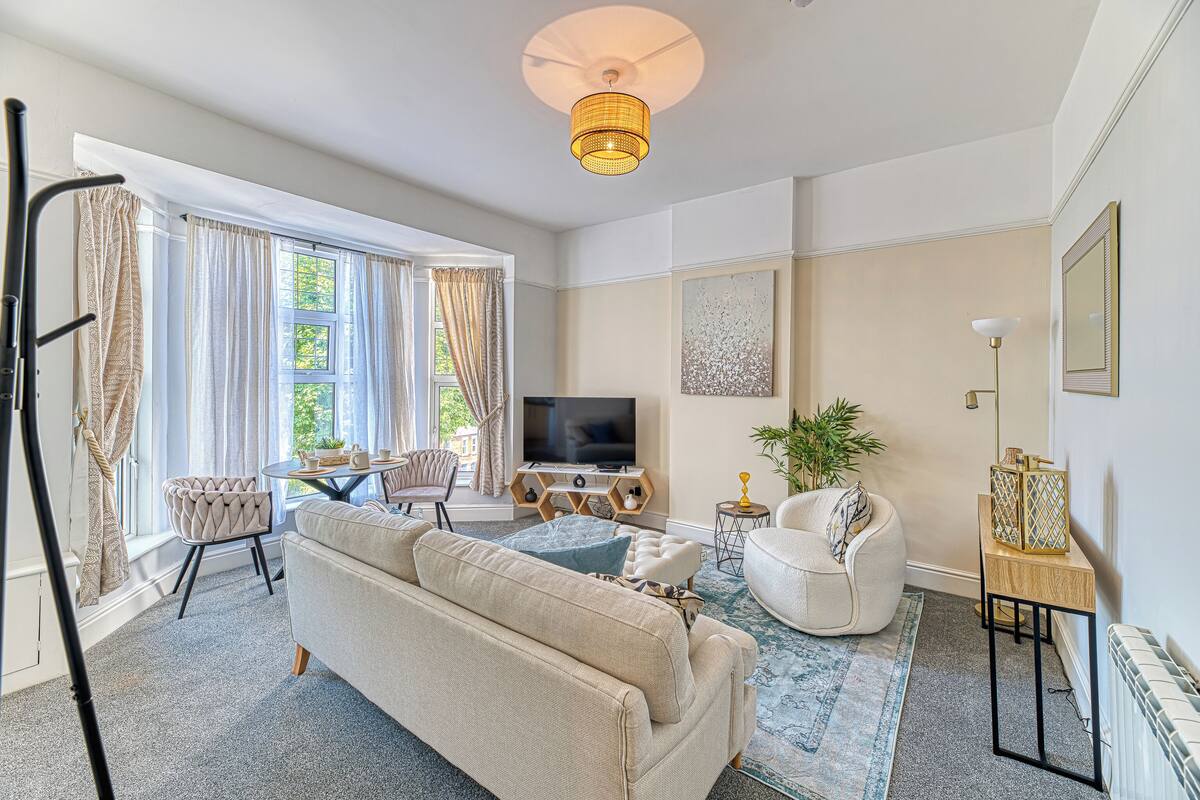 A living room with a sofa, armchair, TV, and a small table with decorative items.