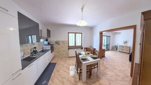 Una cucina moderna con mobili bianchi, un'area pranzo con tavolo apparecchiato per quattro persone e vista sul soggiorno.