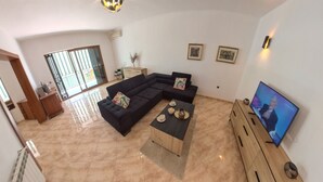 Un soggiorno con un divano componibile, un tavolino, una televisione e un'ampia finestra con vista.