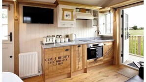 Eine Küche mit Holzausstattung, einem eingebauten Backofen, einer Spüle und einem Fernseher über der Arbeitsfläche.