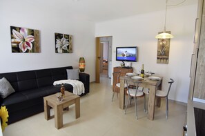 A modern living room with a black sofa, wooden coffee table, dining table with chairs, a TV, and artwork on the walls. - Comfortable stay near Umag center (Umag)