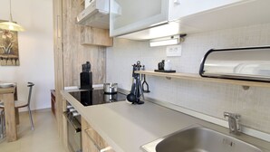 Eine moderne Küche mit Spüle aus Edelstahl, Holzschränken und einem Einbauofen.
