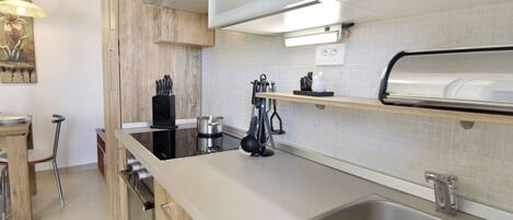 A modern kitchen with a stainless steel sink, wooden cabinets, and a built-in oven.