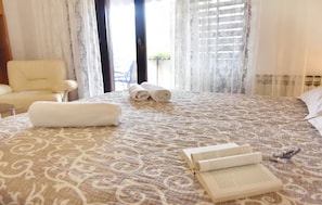 A hotel room with a large bed, a chair, and a view of the outdoors. - Quiet stay with garden view (Umag)