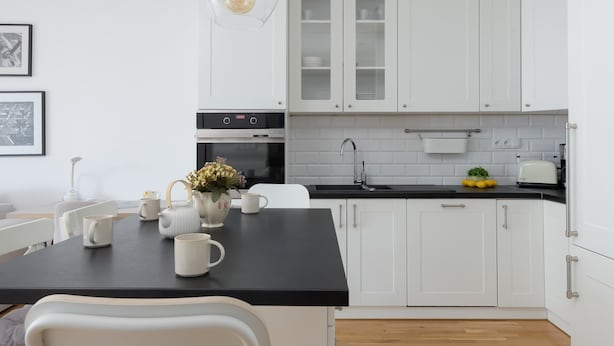 A modern kitchen with white cabinets, a black countertop, and a hanging light fixture. - Modern Apartment | Balcony and Workspace (Warszawa)