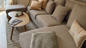 A cozy living room with a sofa, ottoman, and a lamp.