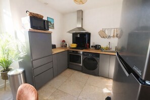 A compact kitchen with a microwave, oven, washing machine, and a refrigerator. - Beautiful, quiet apartment, 5 mn from town center, 10 mn from Almanarre beach (Hyères)