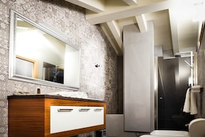 Un bagno con un mobile contenitore in legno, uno specchio grande, una doccia e un water.