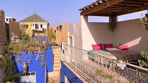 A bedroom with a bed, a balcony with a railing, and a view of a building with a green roof. - Paradise Riad in Marrakech Medina with Rooftop Terrace, sleeps 12 (Marrakech)