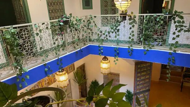 A courtyard with a blue floor, decorative metal railings, hanging lanterns, and potted plants. - Paradise Riad in Marrakech Medina with Rooftop Terrace, sleeps 12 (Marrakech)