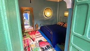 A room with a bed, a mirror, a wall-mounted light, and a patterned rug. - Paradise Riad in Marrakech Medina with Rooftop Terrace, sleeps 12 (Marrakech)