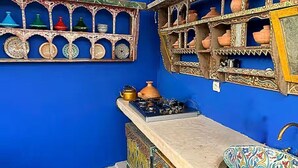 A kitchen with a blue wall, shelves with pottery, a gas stove, and a sink with a decorative basin. - Paradise Riad in Marrakech Medina with Rooftop Terrace, sleeps 12 (Marrakech)