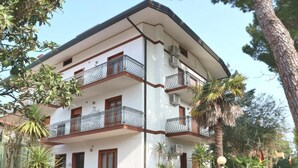 Un edificio de varios pisos con balcones, una escalera y plantas en macetas.
