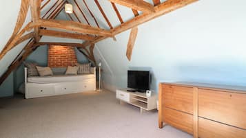 Un dormitorio tipo loft con techo inclinado, una cama, un televisor y un aparador.