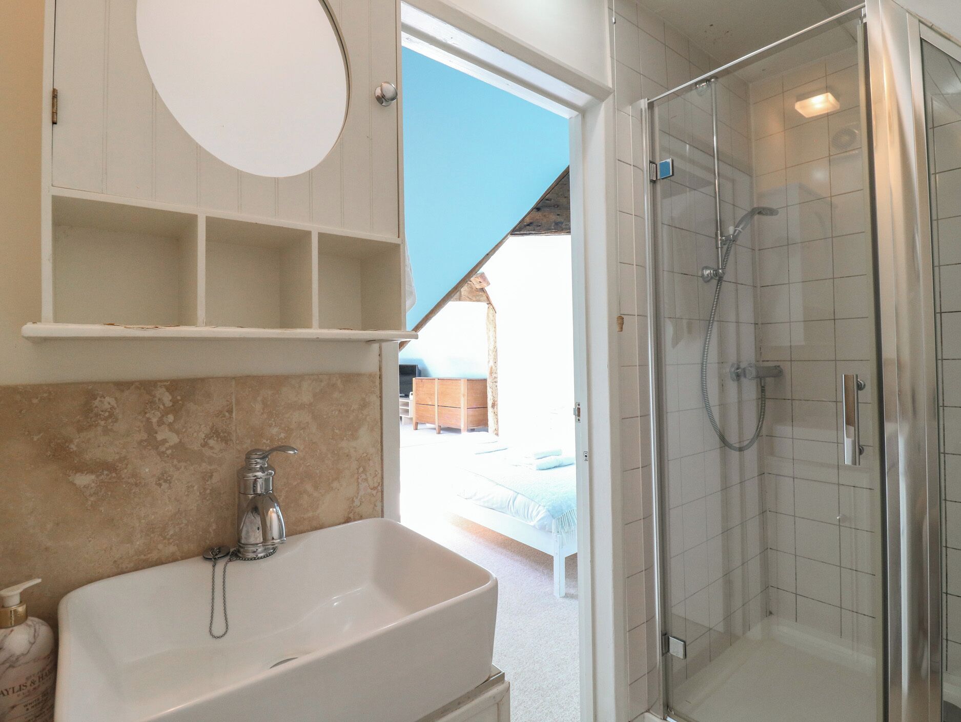 Ein Badezimmer mit Waschbecken, Spiegel, Dusche und Ausblick ins Freie.
