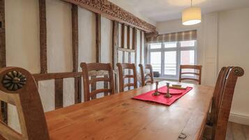 A wooden dining table with six chairs, a red placemat, and candle holders.