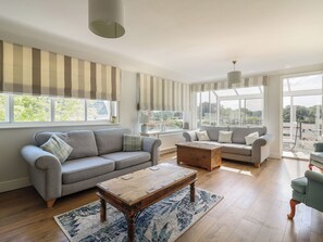 A spacious living area with a grey sofa, a wooden coffee table, and a patterned rug. - Beresford House (Woodbridge)