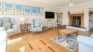 Una sala de estar con chimenea, televisor y estantería.