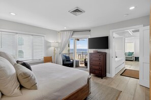 Ein Schlafzimmer mit Bett, Kommode, Fernseher und einem Balkon mit Aussicht.
