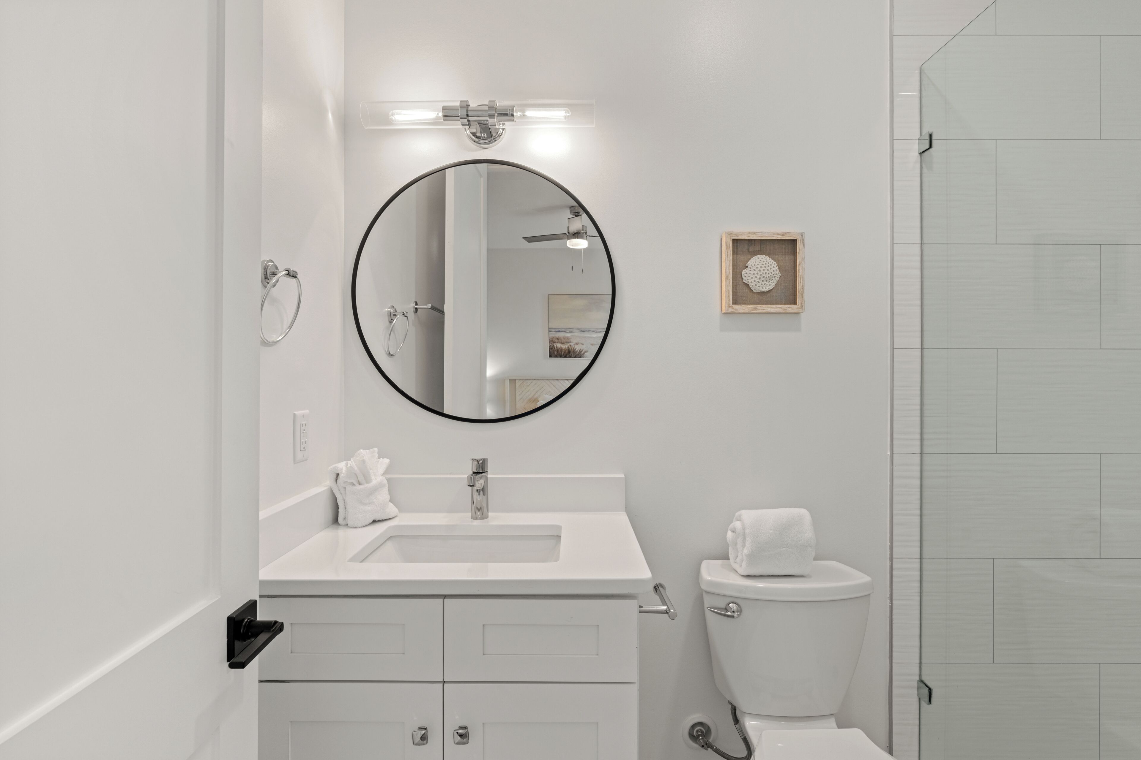 Een moderne badkamer met een ronde spiegel, een wit wastafelmeubel en een toilet.