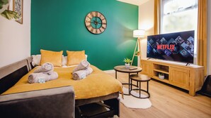 Een hotelkamer met een bed, een televisie, een klok en een raam.