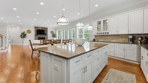 A spacious kitchen with white cabinetry, a large island, pendant lighting, and a stone backsplash. - Lakefront Retreat • Private Dock + Firepit + Game Room | Montclair Manor (Mooresville)