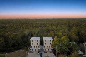 Ein zweistöckiges Gebäude mit einer symmetrischen Fassade, umgeben von dichtem Wald und klarem Himmel.