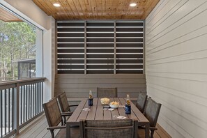 A wooden deck with a table set for four, featuring a bowl of chips, two bottles of beer, and playing cards. - 20% Off First 3 Bookings! | Sleeps 32 • Pool + Game Room + Golf Carts (Santa Rosa Beach)