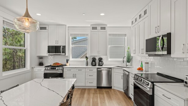 Una cocina moderna con armarios blancos, electrodomésticos de acero inoxidable y una isla grande.