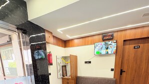 Un vestíbulo de hotel con una recepción, un sofá, un televisor y una puerta de madera con el número 101.