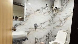 Un baño con pared de mármol, un lavabo, un inodoro y un bidé.