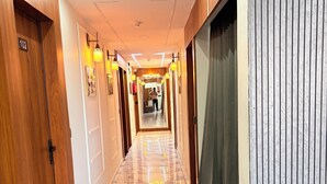 Un pasillo de hotel con suelo de mármol, puertas de madera e iluminación moderna.