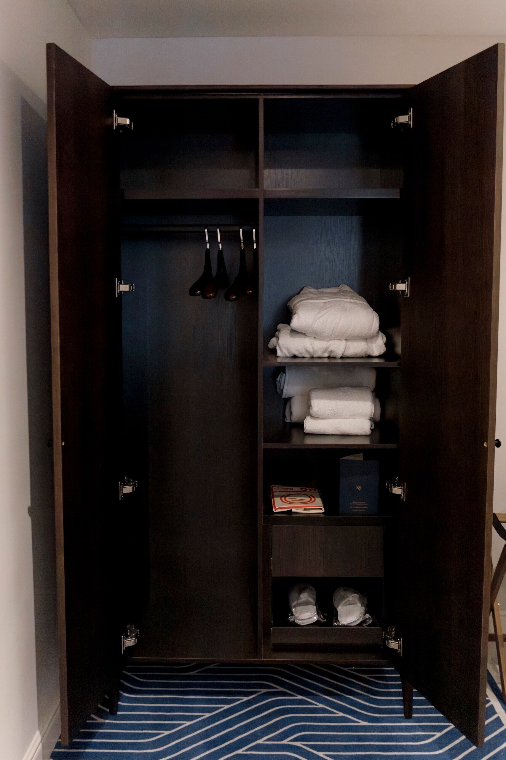 A dark wooden wardrobe with multiple shelves, a hanging rod, and a shoe rack.