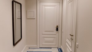 A hallway with a white door, a mirror, and a blue patterned rug. - Pana Unique Semey (Semipalatinsk)