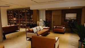 A modern living room with a sofa set, a bookshelf, a coffee table, and a large potted plant. - Pana Unique Semey (Semipalatinsk)
