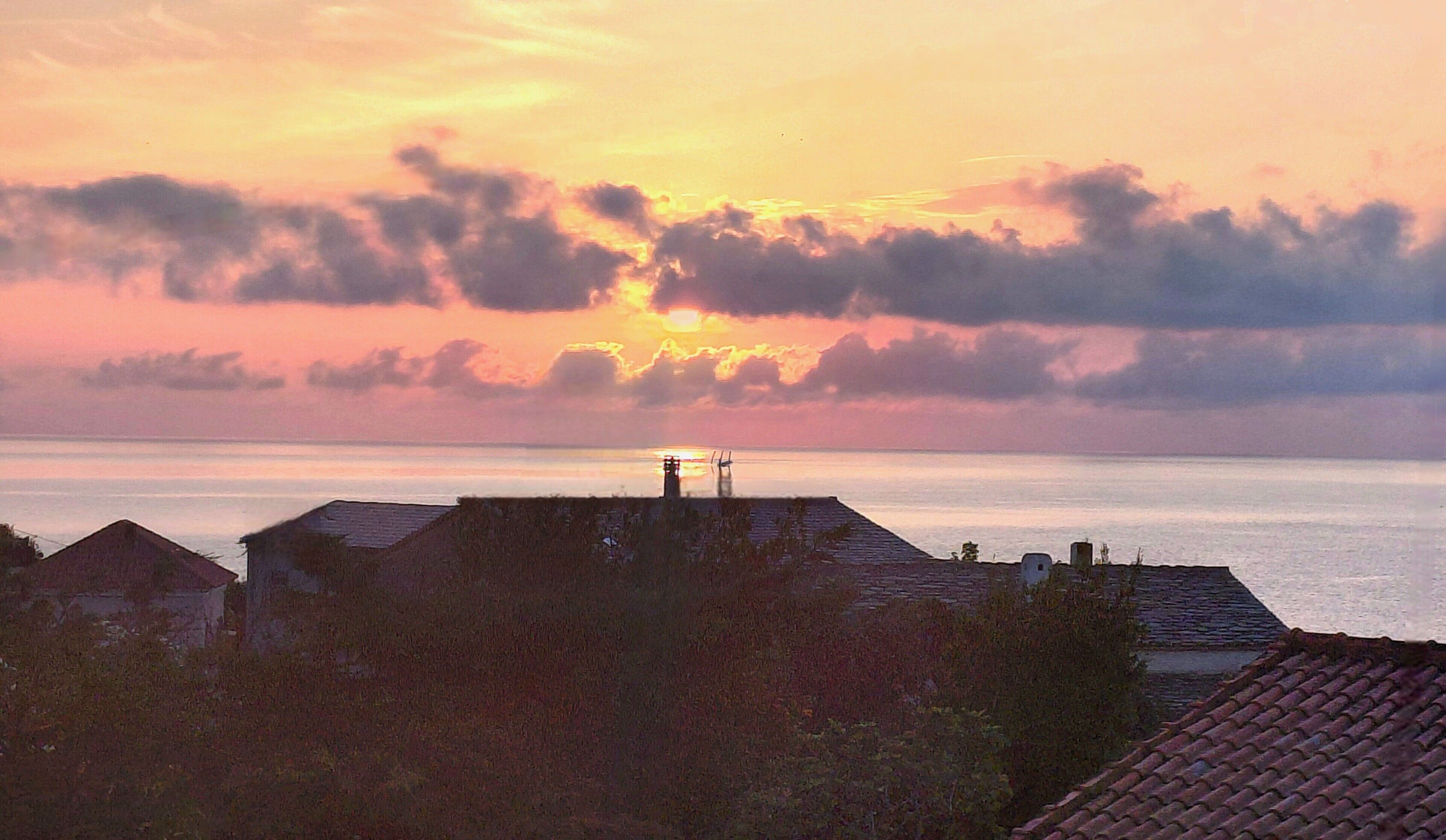 A coastal sunset with buildings in the foreground.