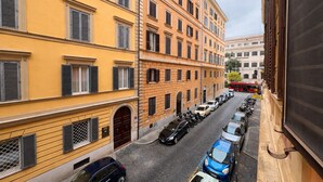 Una calle estrecha flanqueada por vehículos estacionados y edificios de estilo arquitectónico uniforme.