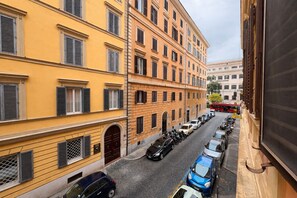 A narrow street lined with parked cars and buildings with uniform architectural style. - Esedra Loft, Like on a Boat Drifting Through Rome (Rome)