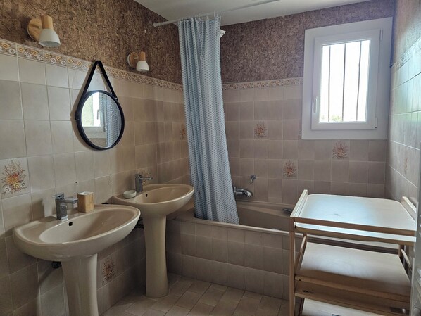 A bathroom with two sinks, a bathtub, a mirror, and a window.