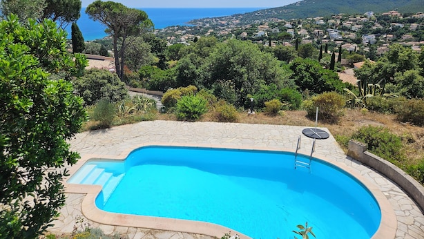 Una piscina con vistas a un pueblo costero y colinas.