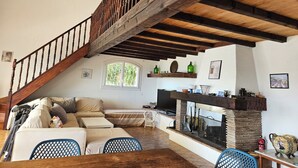 Amplia sala de estar con escalera de madera, chimenea y televisor.