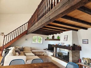 Ein geräumiger Wohnbereich mit einer Holztreppe, einem Kamin und einem Fernseher.