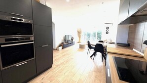 A modern kitchen with built-in appliances, a dining area with a table and chairs, and a view of the outdoors through large windows. - Sea view - Large terrace - Walking distance to beaches - Air conditioning - Parking (Bandol)
