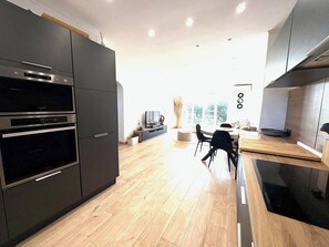 A modern kitchen with built-in appliances, a dining area with a table and chairs, and a view of the outdoors through large windows. - Sea view - Large terrace - Walking distance to beaches - Air conditioning - Parking (Bandol)