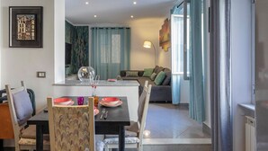 A dining area with a table set for two, a sofa in the background, and a view of the living room. - Sweet Coccagna by Wonderful Italy (Genoa)