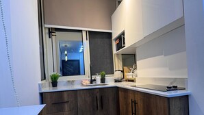 Et moderne køkken med mørke træskabe, en hvid bordplade og en indbygget mikroovn.