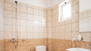 A bathroom with a shower, toilet, sink, and cabinet. - Aggire Summer Suites (Zakynthos)