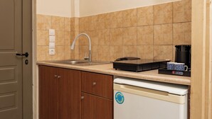 A kitchen with wooden cabinets, a white refrigerator, a sink, and a hanging light fixture. - Aggire Summer Suites (Zakynthos)